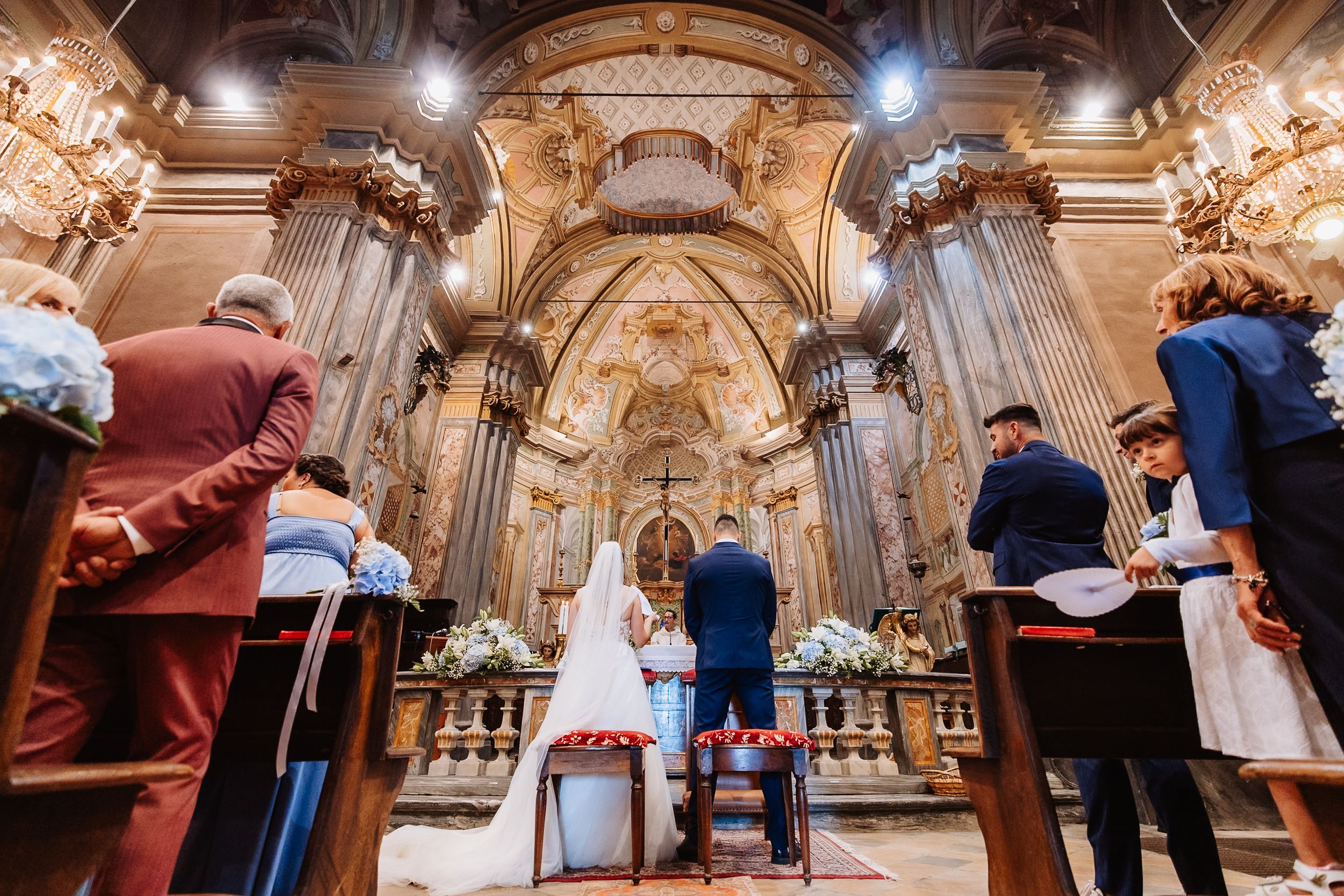 Inside a grand ornate cathedral interior view with arched ceilings and glowing chandeliers.