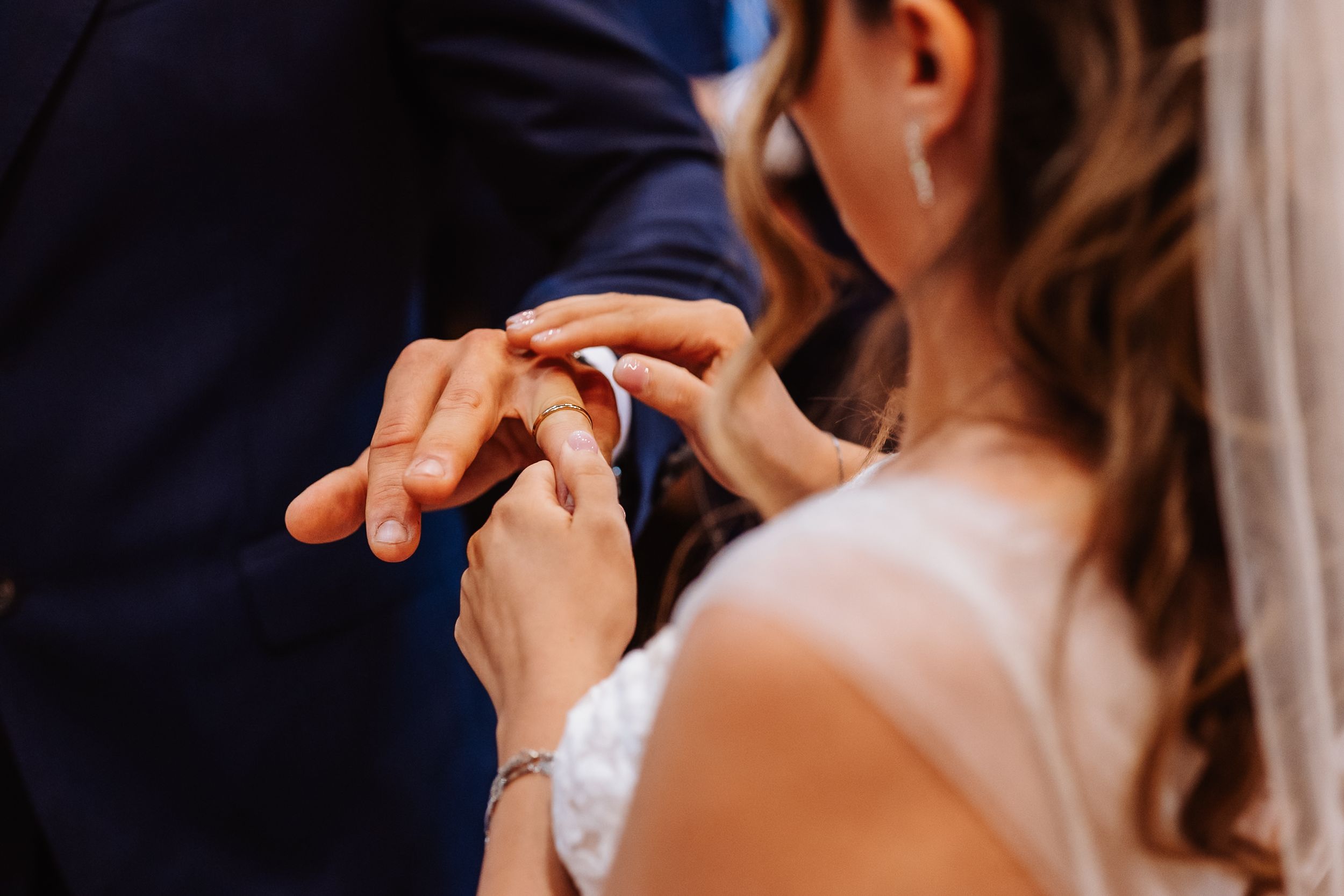 Close-up view of couple's hands joining together during emotional wedding ceremony moment.