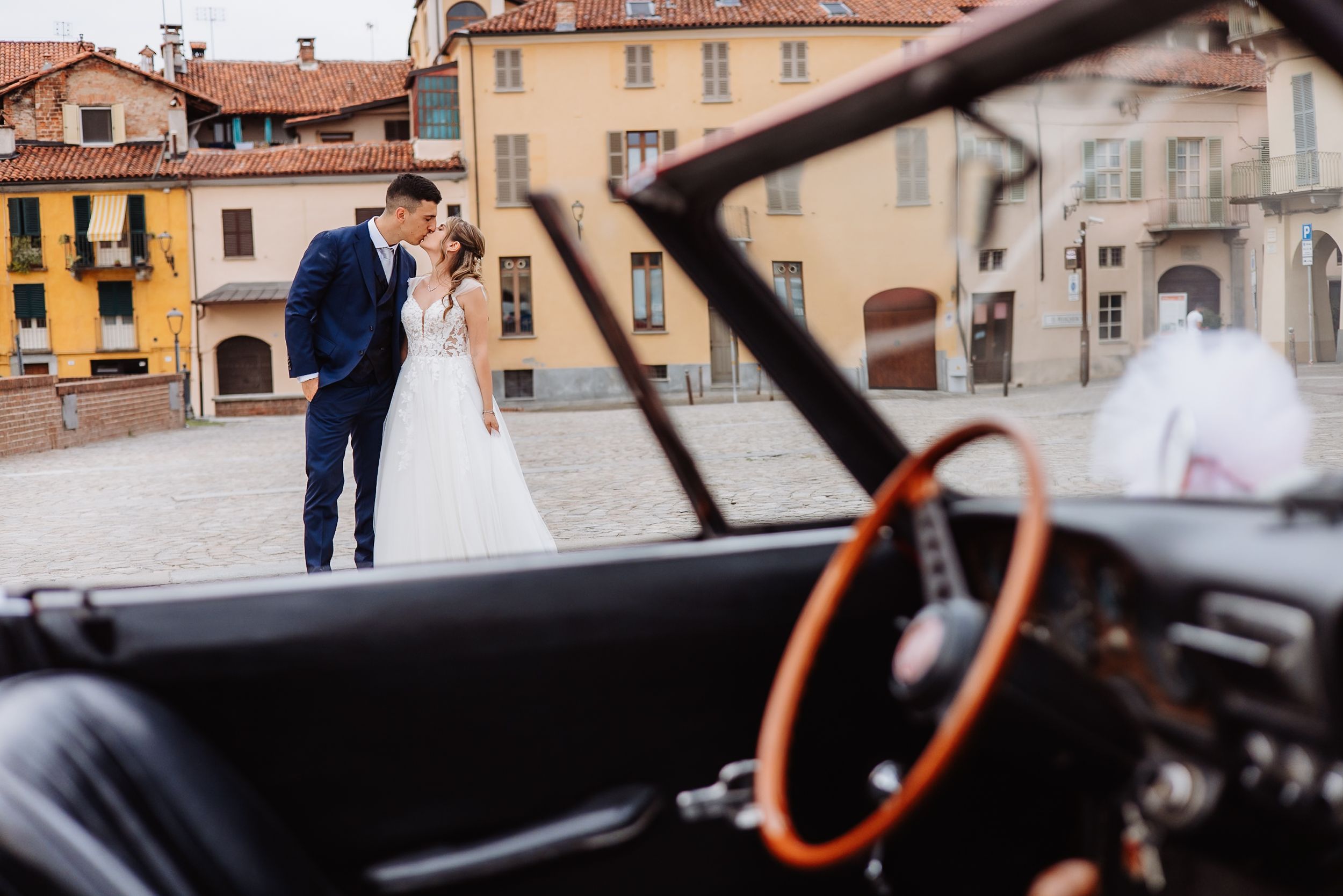 A romantic wedding couple walks through the charming streets of an old European town with historic buildings in view.