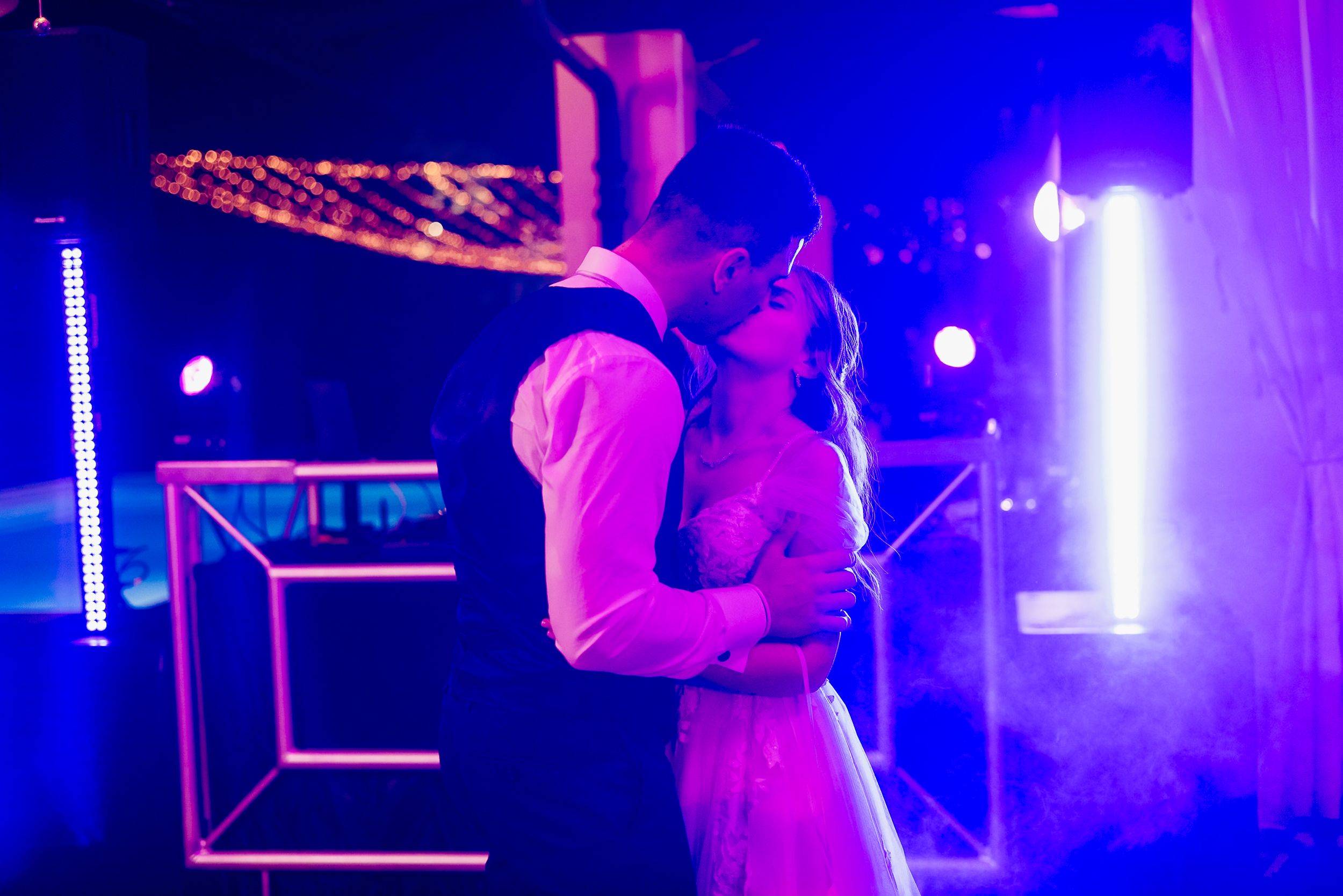 A romantic couple shares an intimate dance moment under purple and blue nightclub lighting.