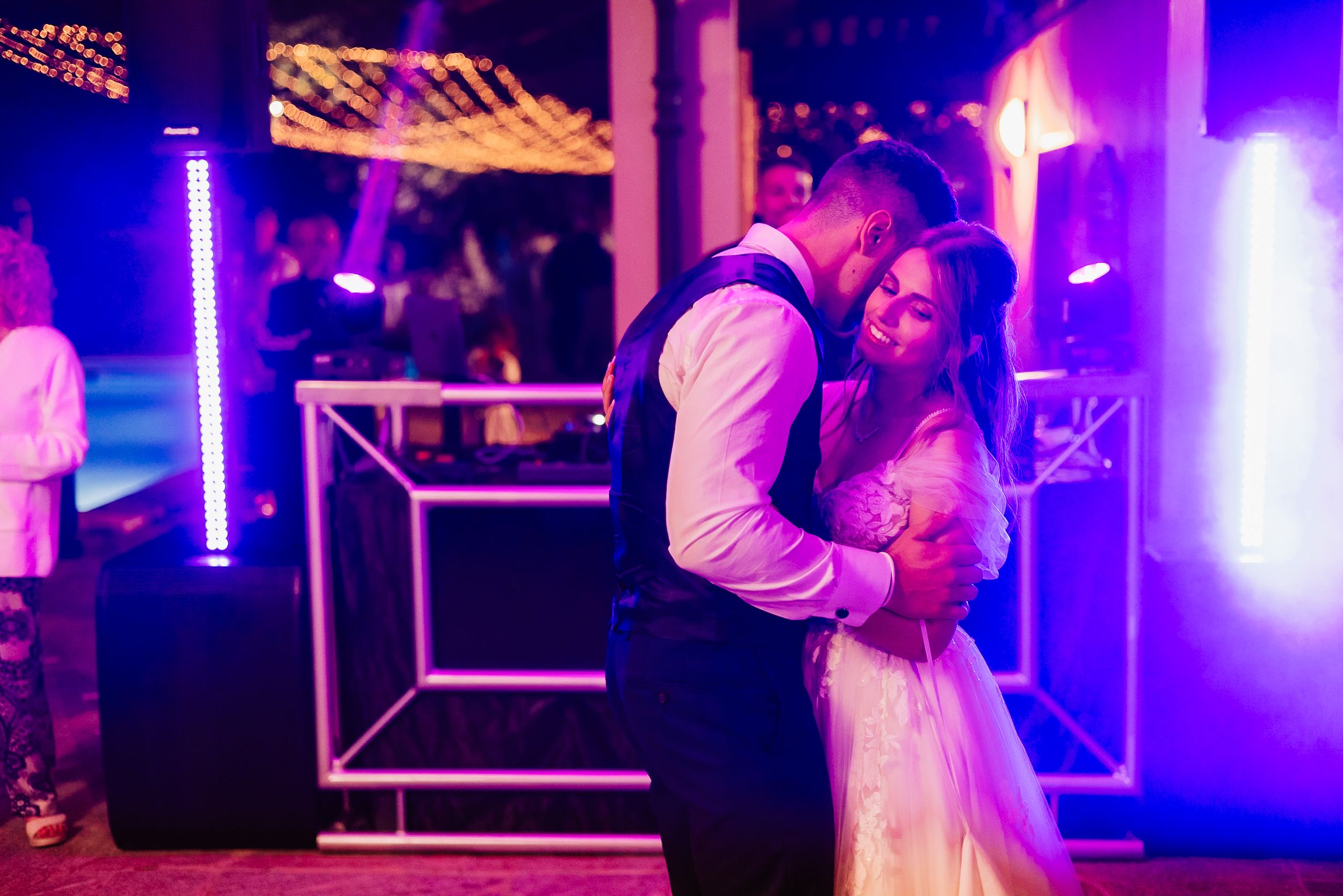 People dancing together at a nightclub with vibrant purple and blue lighting illuminating the dance floor.