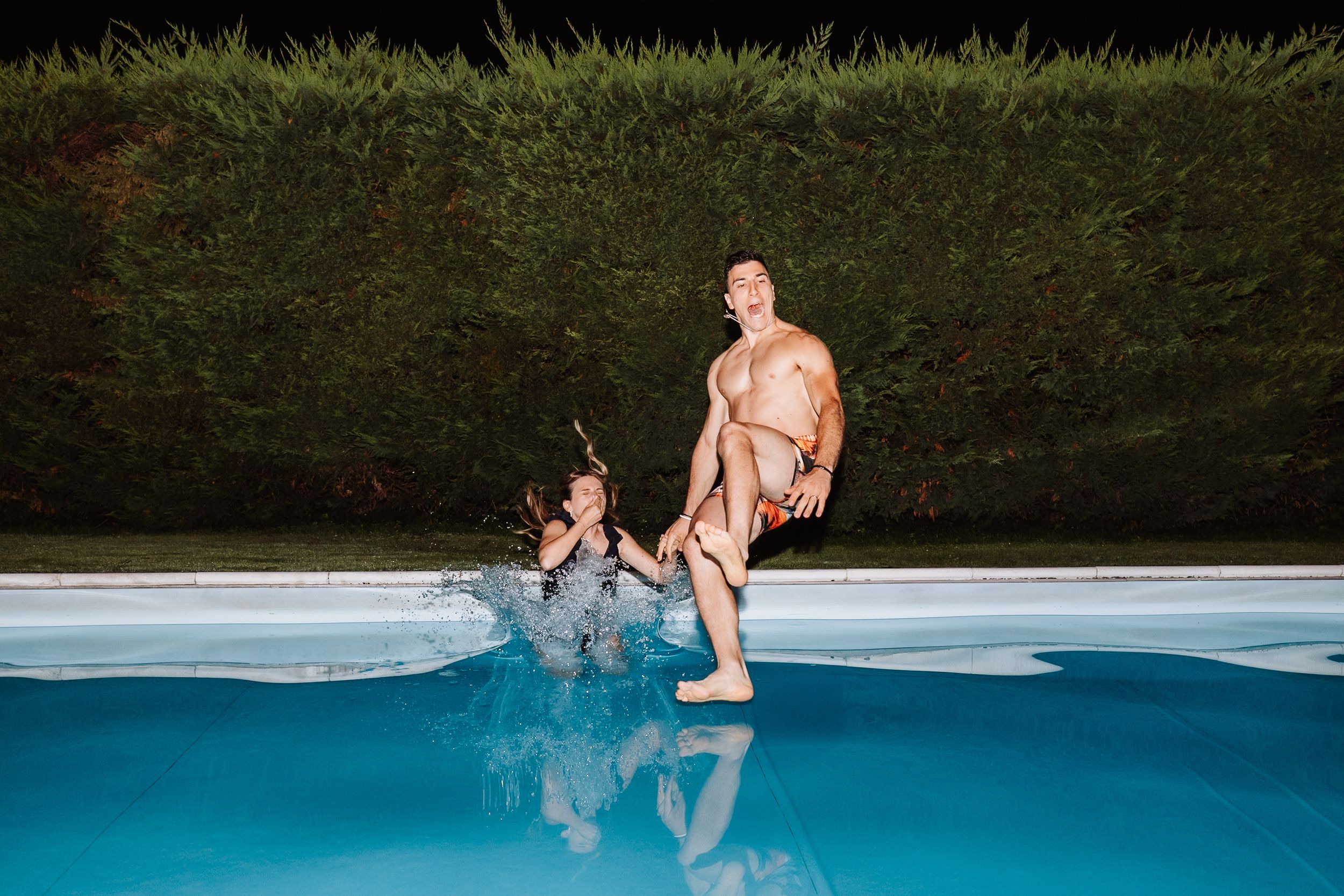 A figure splashes gracefully into a backyard swimming pool on a sunny summer afternoon.