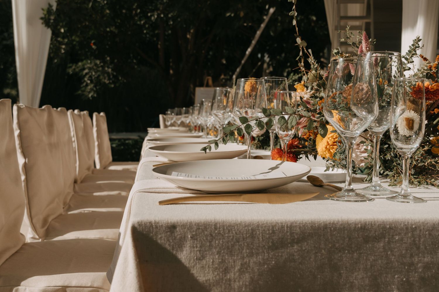 Elegant wedding reception tables set with white linens, glassware and floral centerpieces in a luxurious venue.