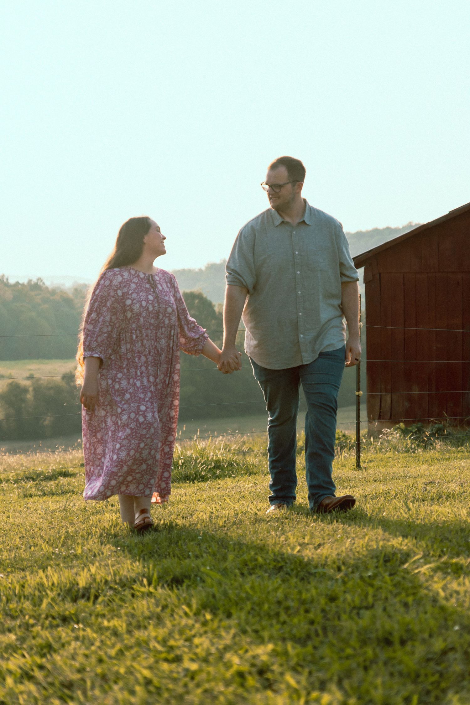 Couple walking and holding hands while walking at farm romantic photo session in bowling green, Kentucky to capture their engagement joy