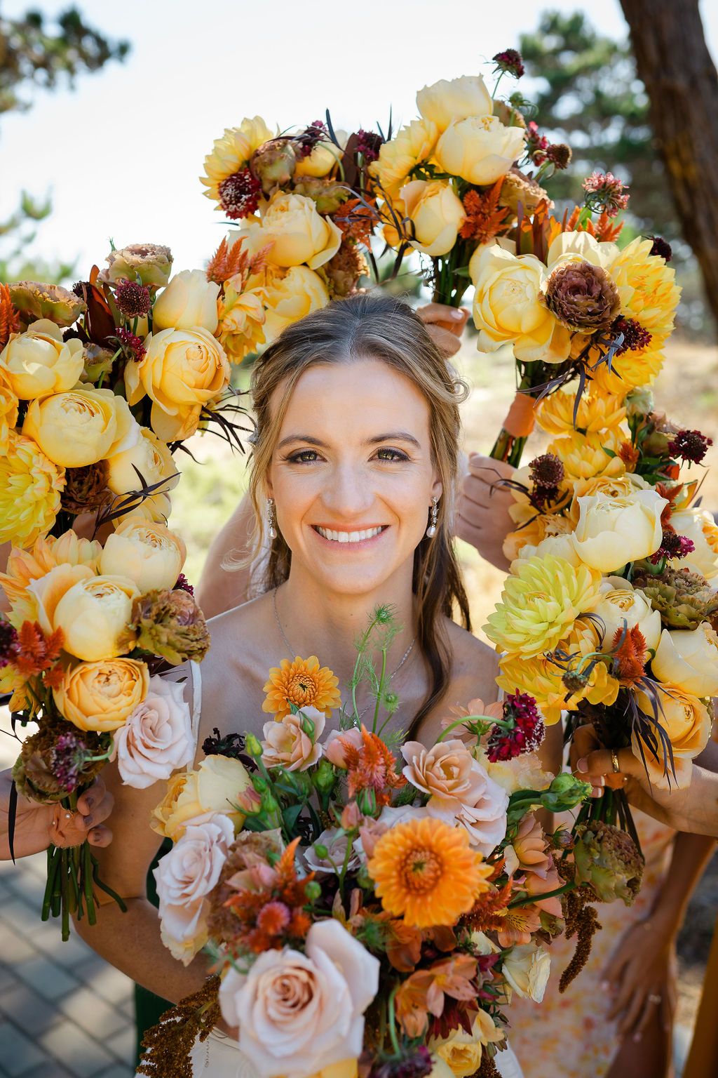 Wooden wedding arbor decorated with yellow sunflowers and greenery against a rustic outdoor landscape.