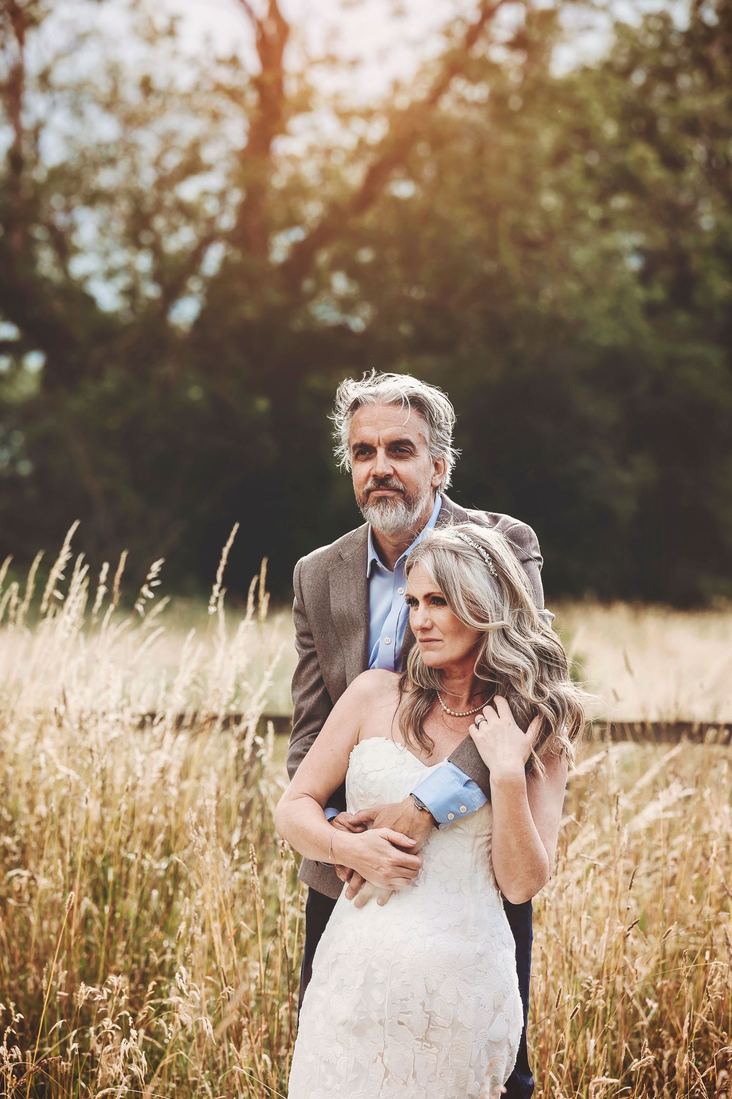 A couple embraces in a golden wheat field at sunset during a romantic outdoor photoshoot.