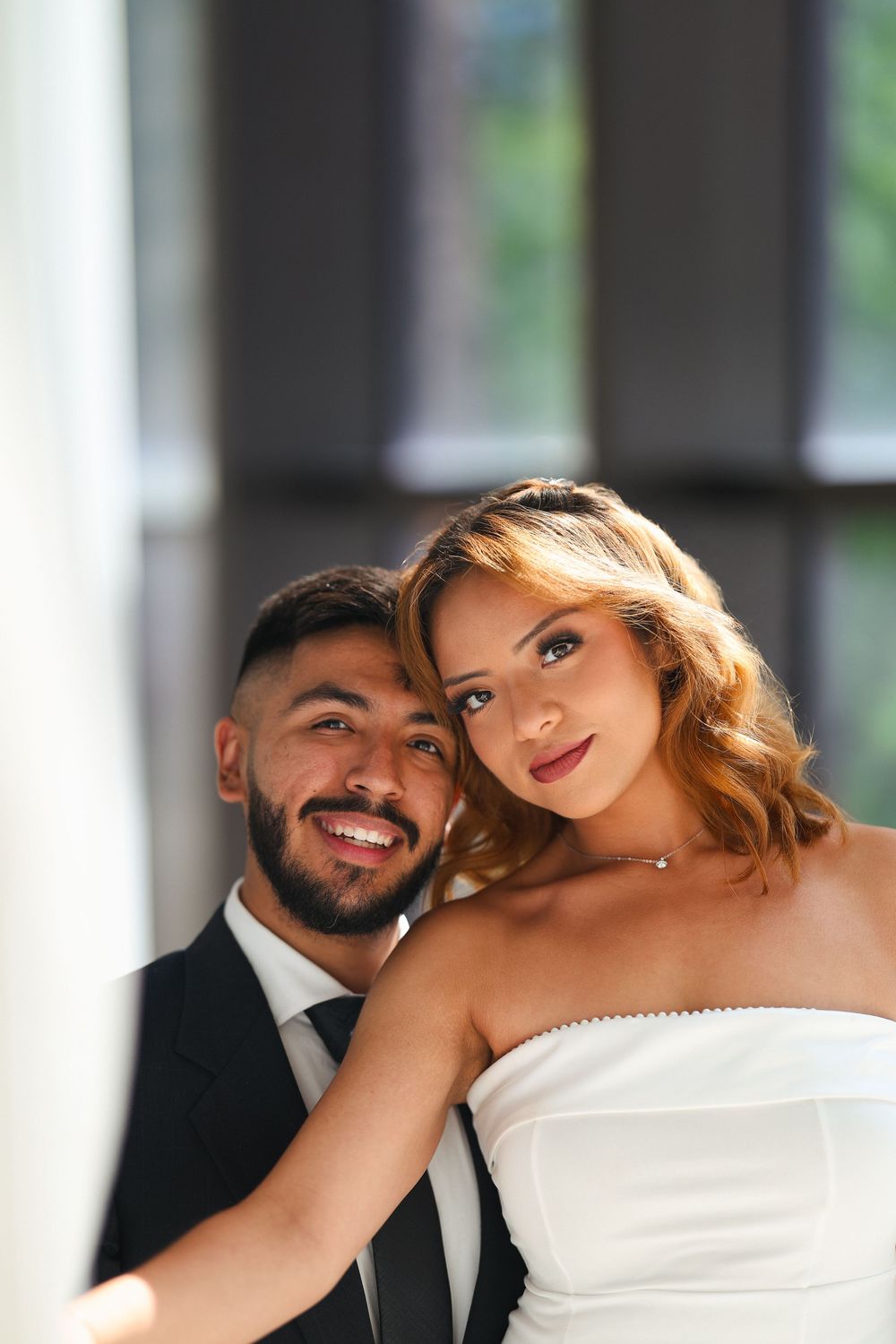 An intimate wedding couple poses for a close-up portrait against a blurred background.