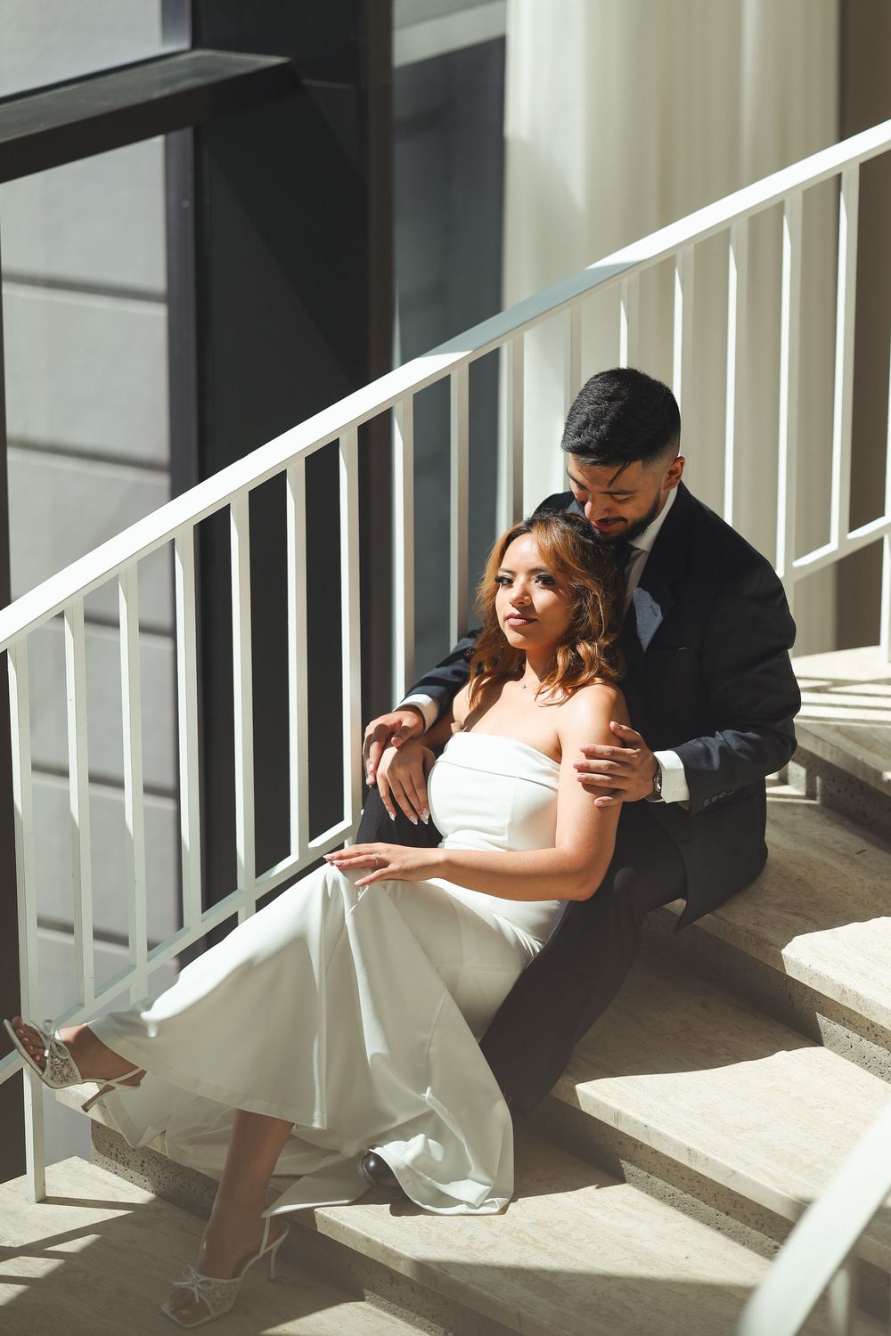 A series of romantic poses on white porch stairs in wedding attire.