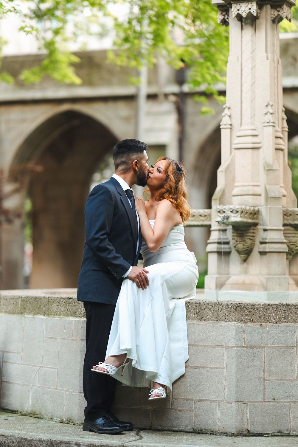 A playful wedding photoshoot on stone steps with Gothic architectural elements.