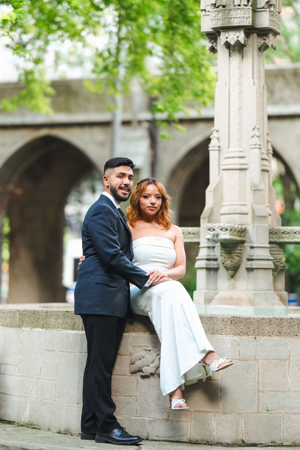 A romantic wedding couple poses together on ornate stone steps outdoors.