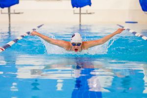 Competitive swimmer performing butterfly stroke in an indoor pool during a swim meet.