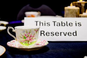 Elegant floral teacup on saucer beside reserved table sign at formal event.