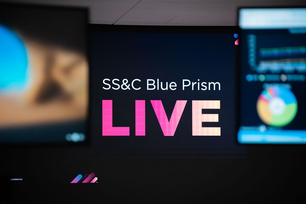 An electronic music concert with colorful blue lighting and visual effects displayed on large screens.