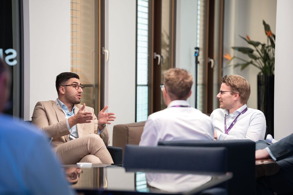 Professional meeting participants having an animated discussion at a modern office conference table.