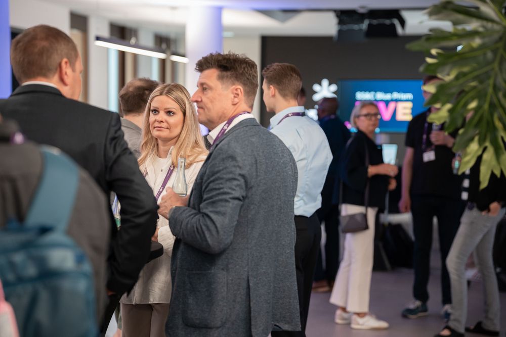 Business professionals engaged in networking conversations at a corporate event in a modern office space.