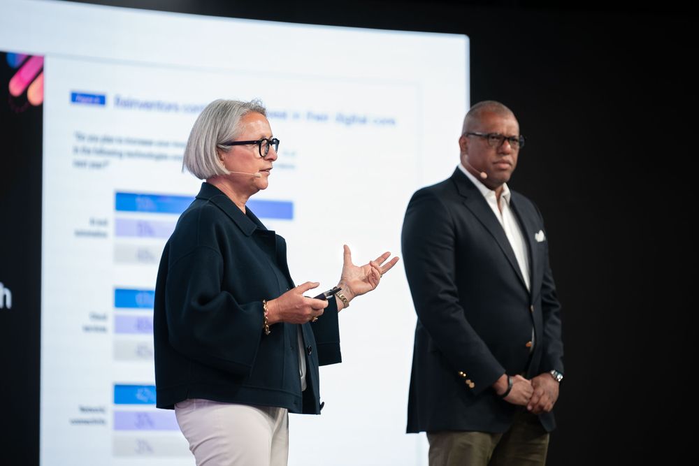 Panel of business professionals engaged in discussion during a conference presentation on stage.