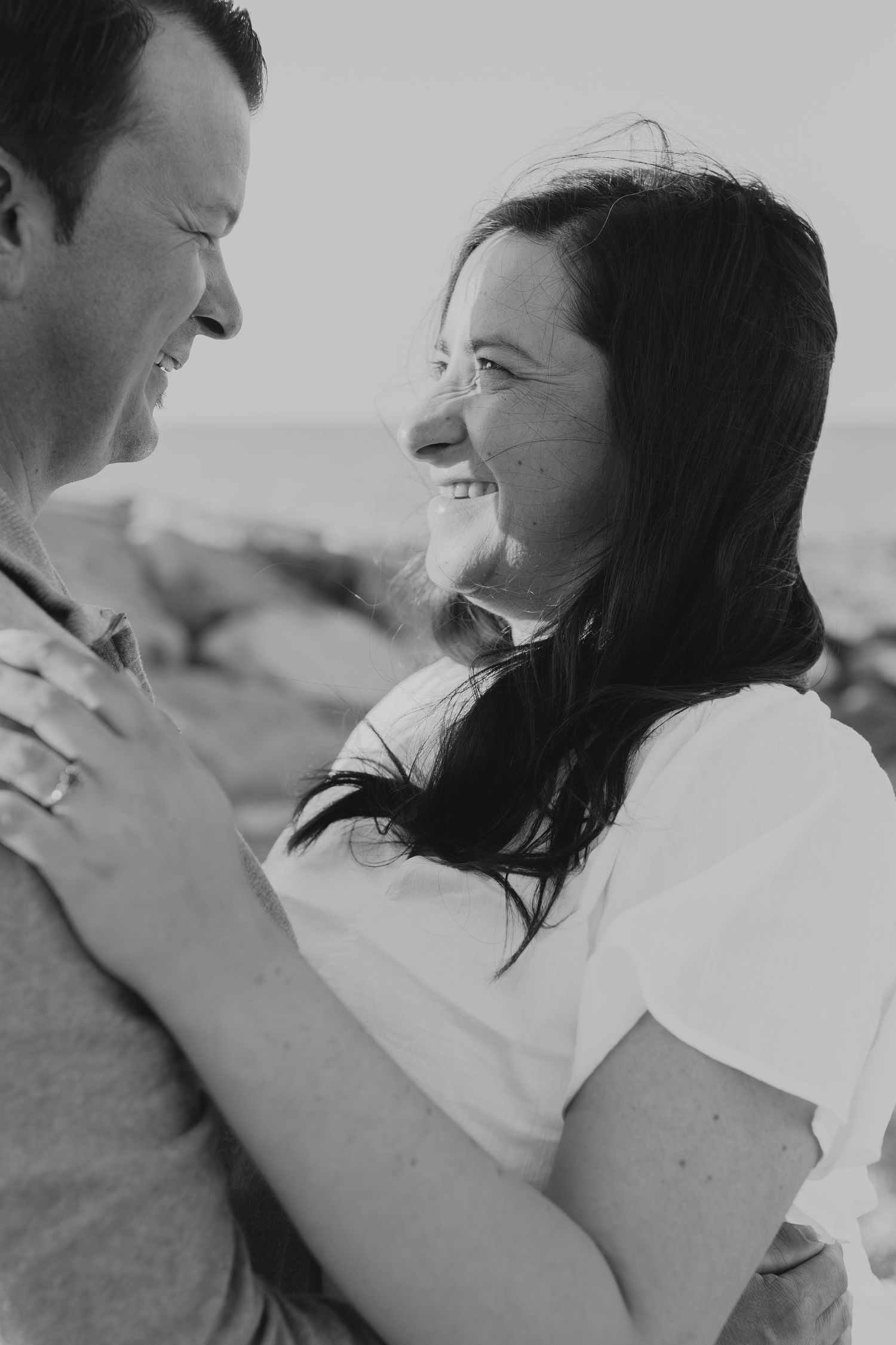 Black and white portrait of a couple sharing a joyful laugh while embracing.