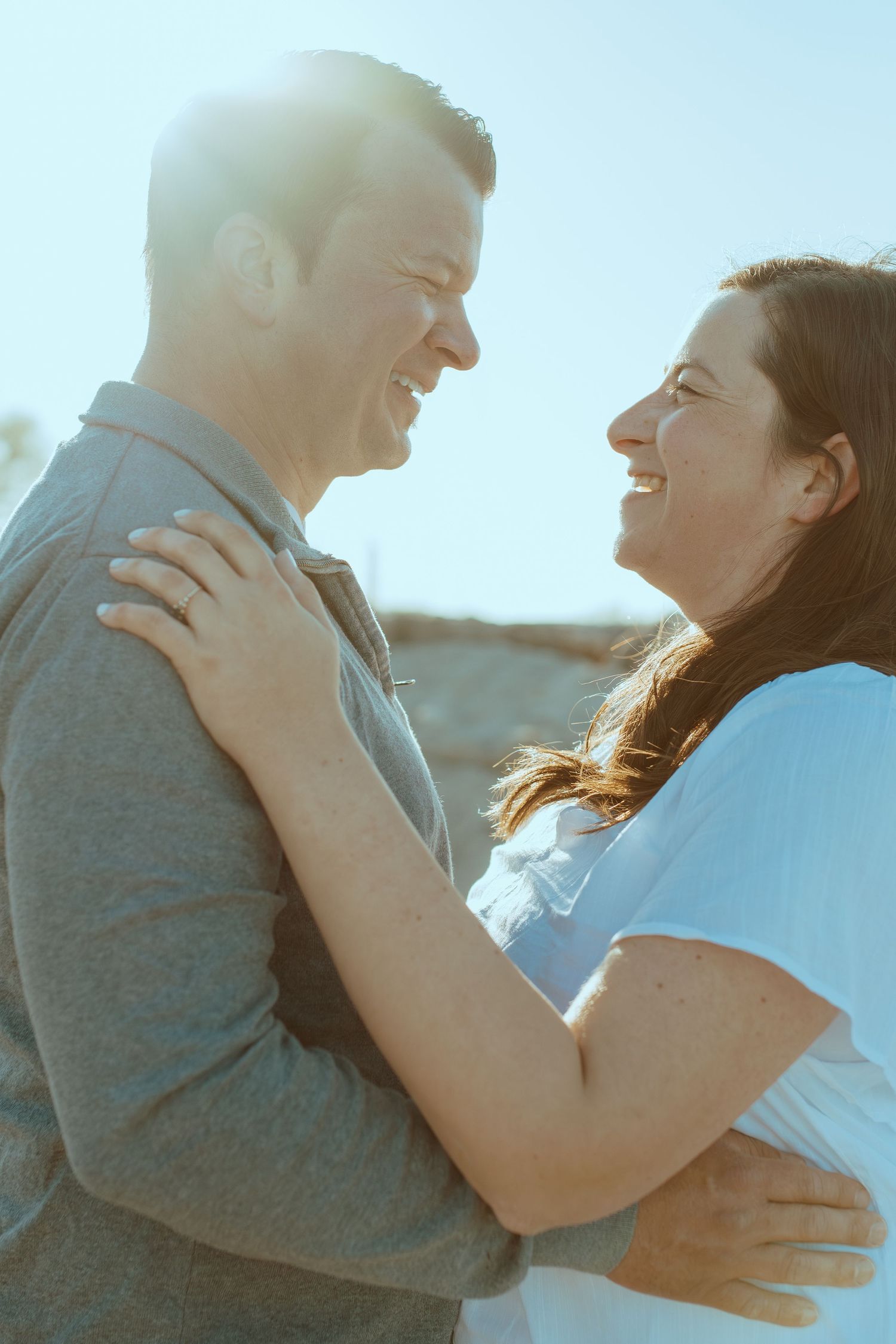 Sun-drenched portrait of a couple embracing by the ocean.