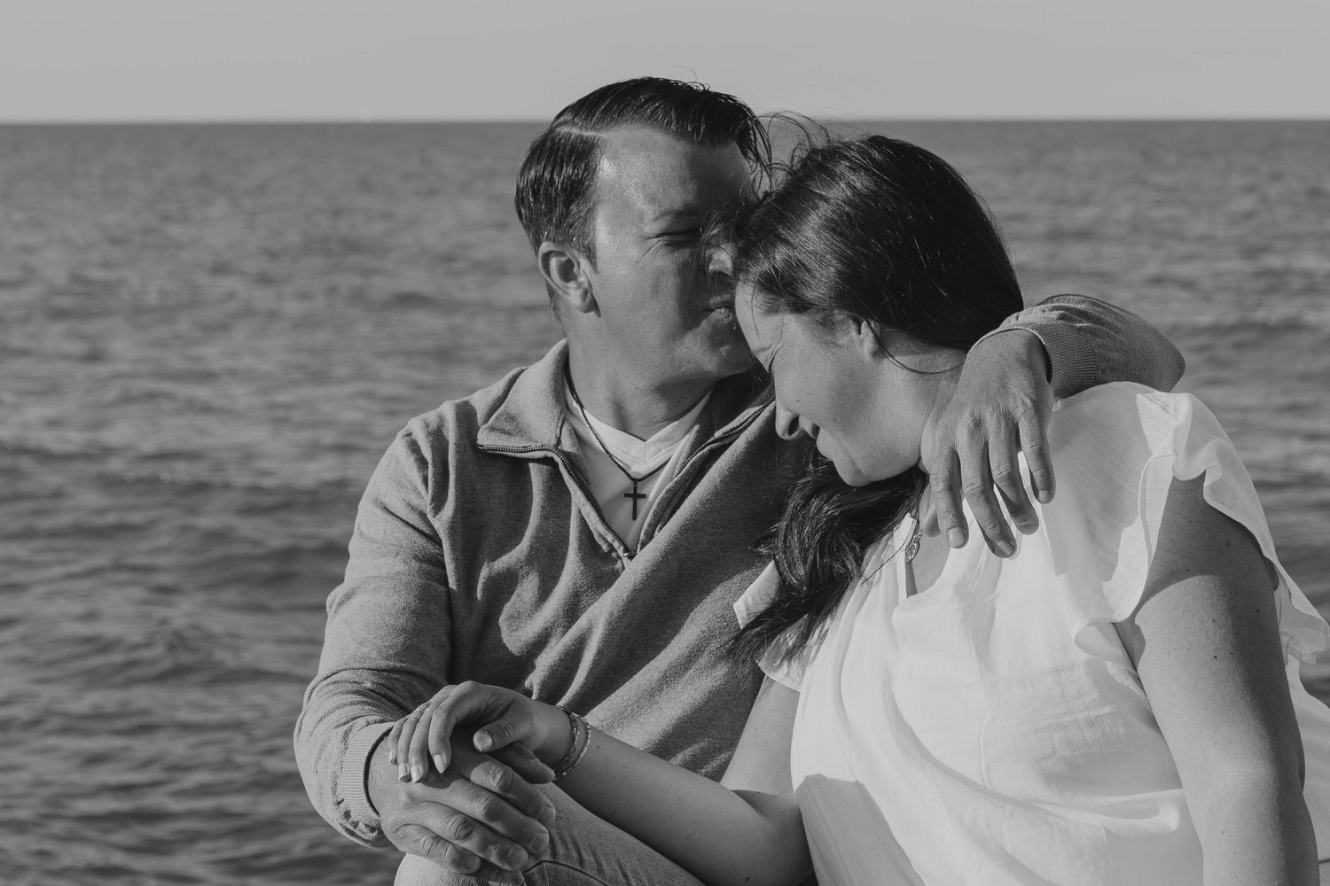 Sweet romantic couple sharing a tender moment together on the beach during a gray overcast day.