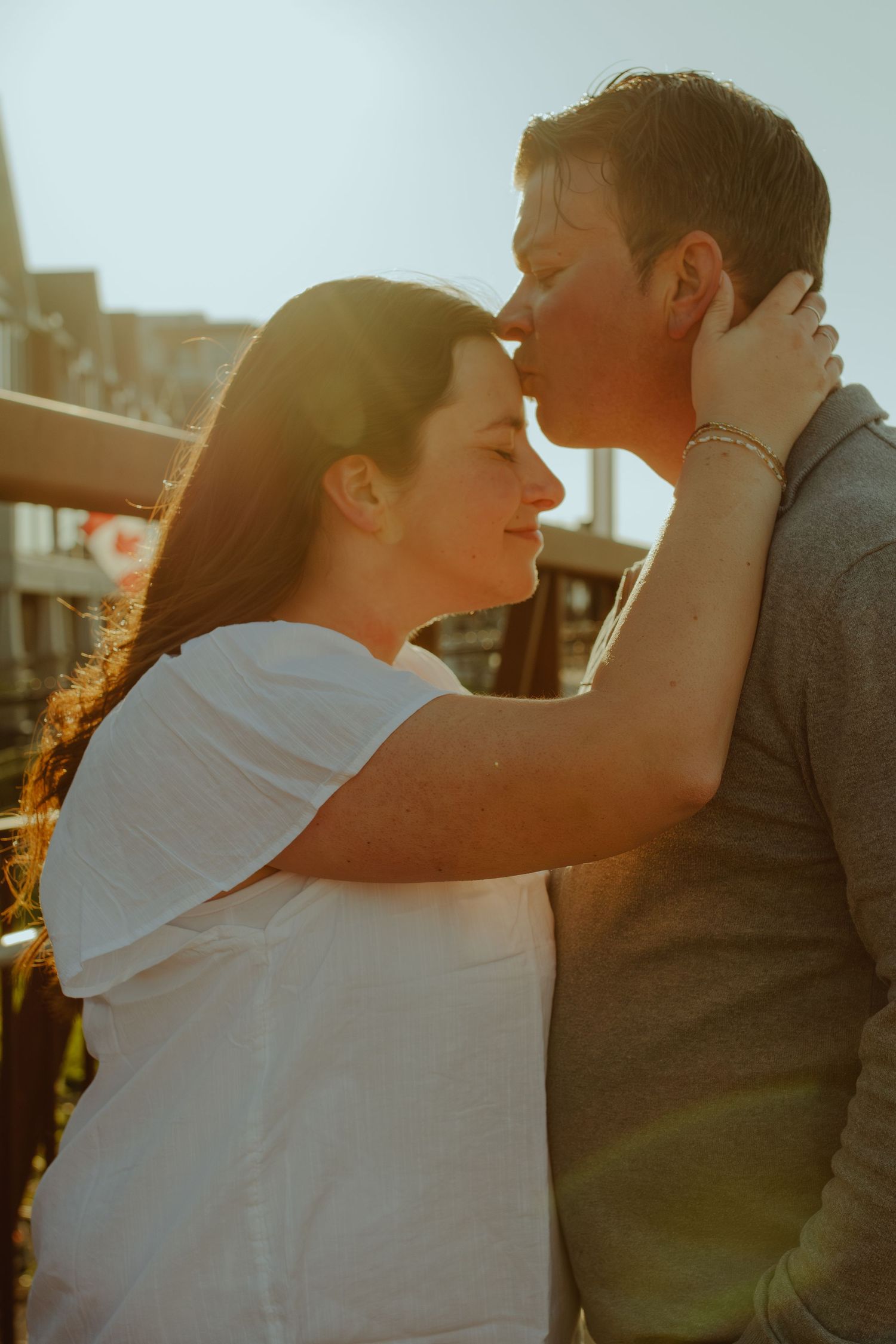 Loving couple embracing in golden sunset light with urban backdrop.