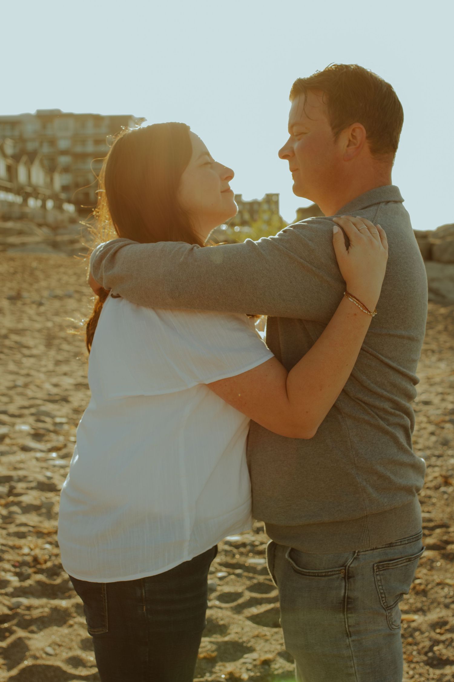 A tender embrace shared between a couple on a beach during golden hour.
