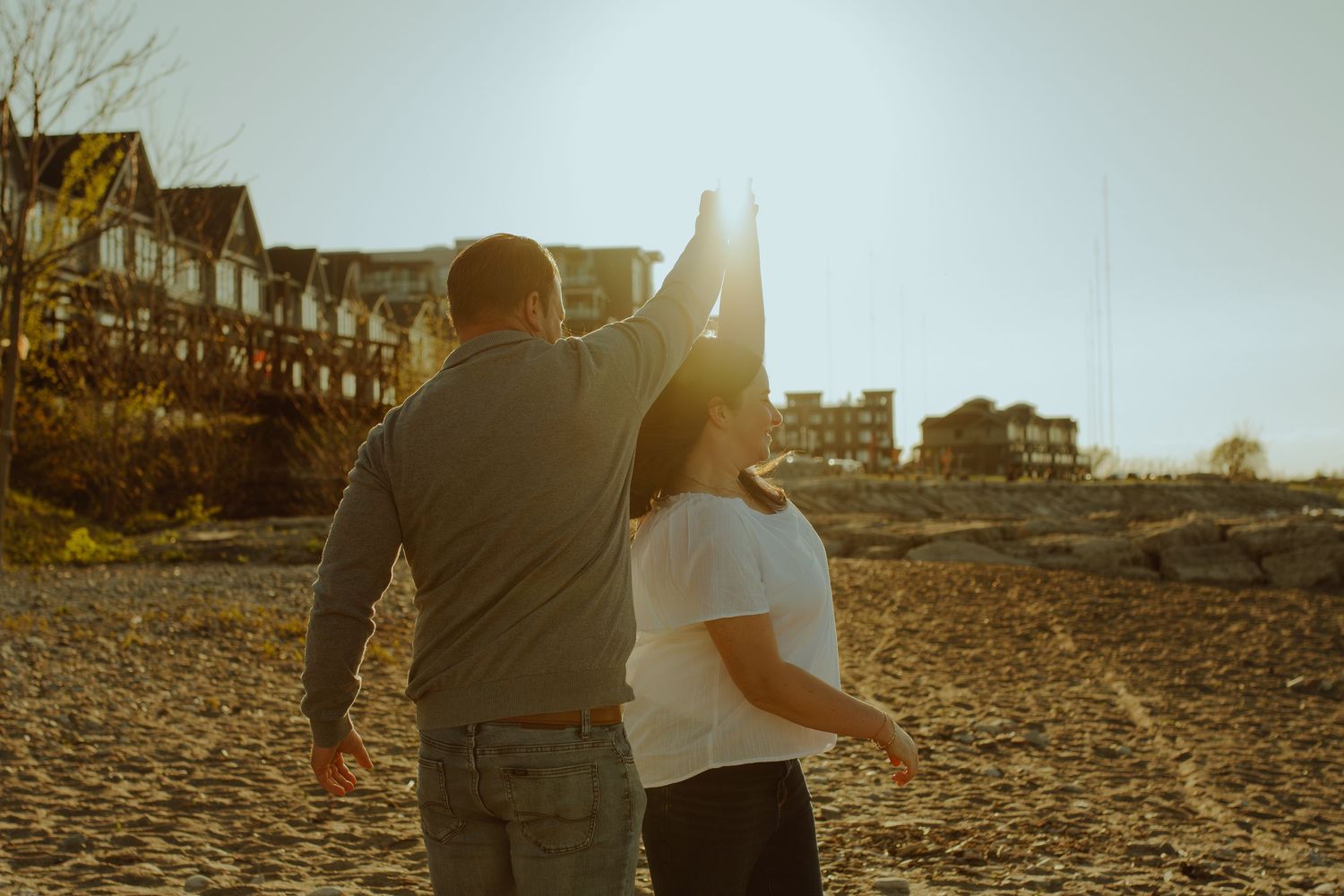 Couple walking along rocky shoreline at golden hour.