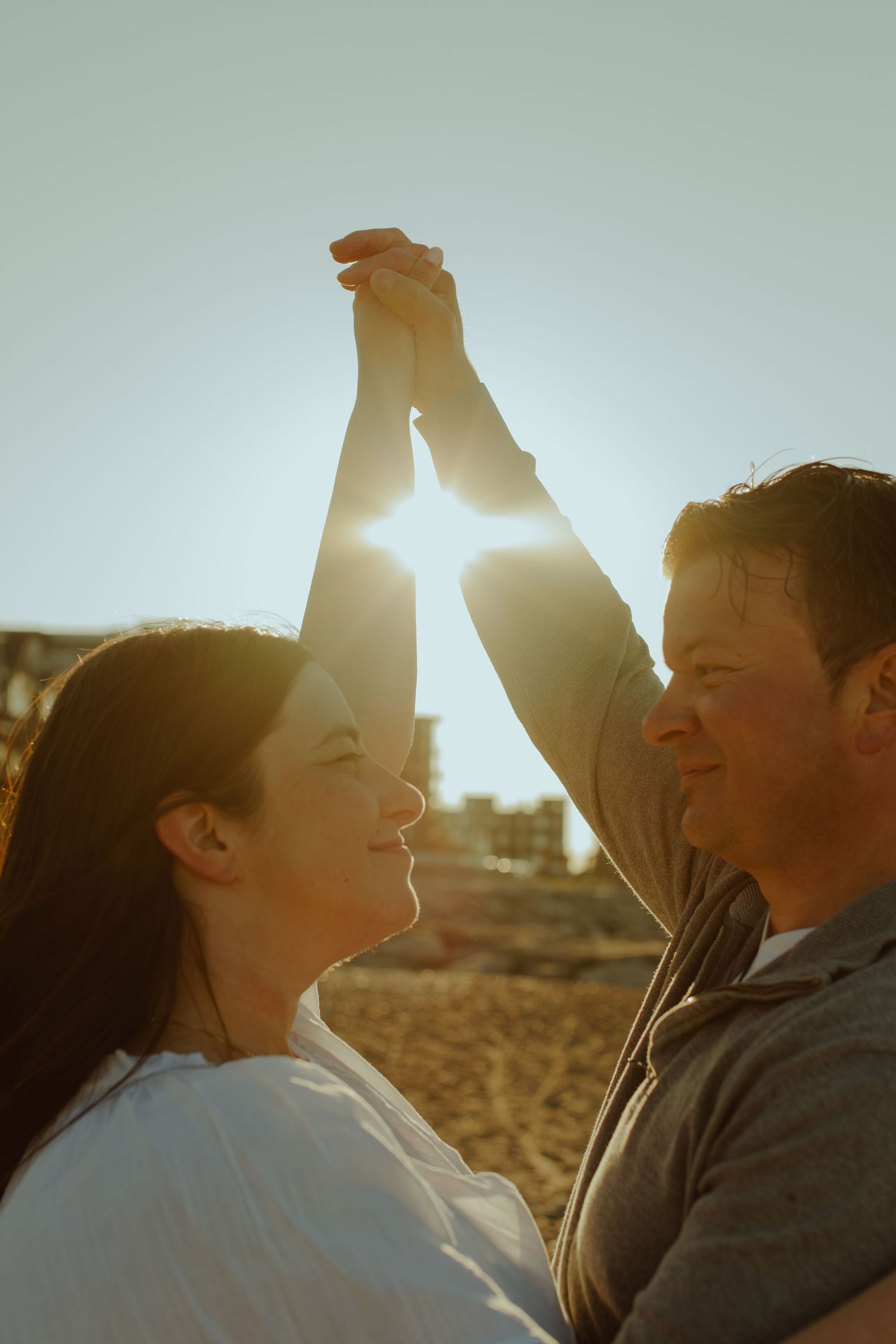 Backlit couple laughing together in soft evening sunlight.