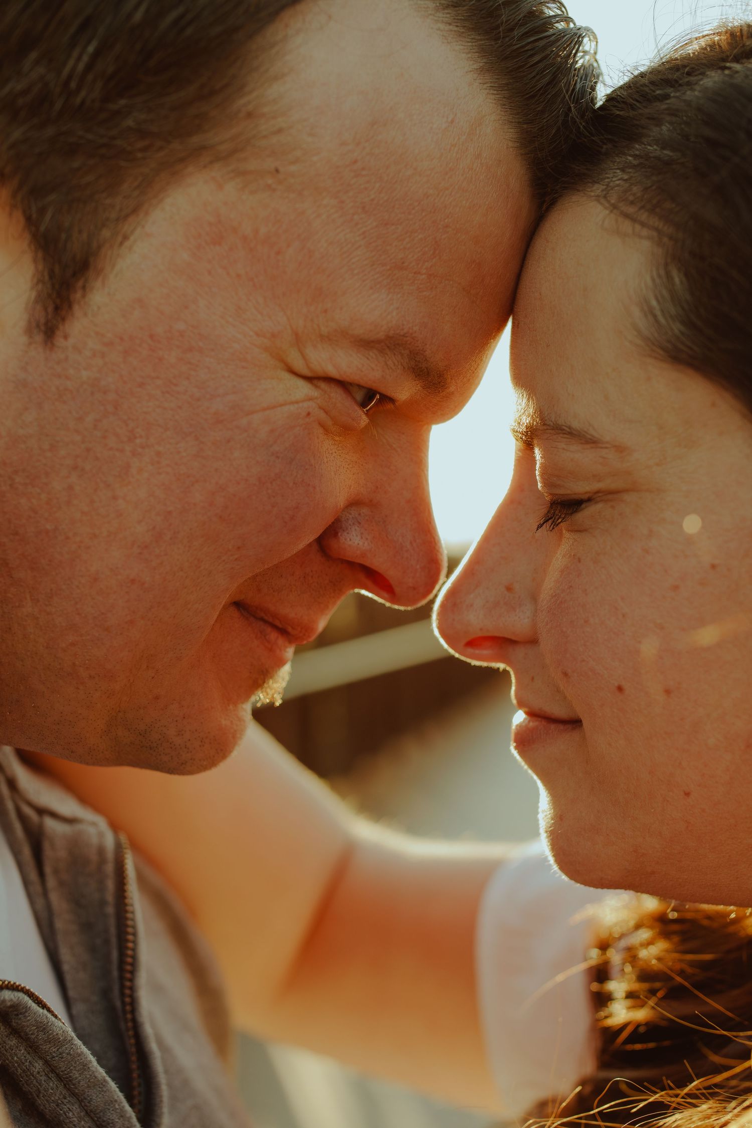 Romantic close-up shot of a couple sharing an intimate moment in warm sunlight.