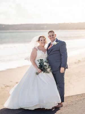 Newlyweds share intimate moments during sunset beach wedding photos with soft golden light.