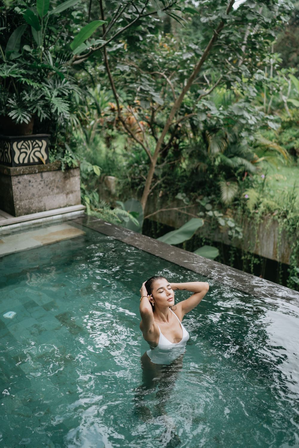A peaceful scene in a luxury infinity pool nestled among tropical trees and plants.