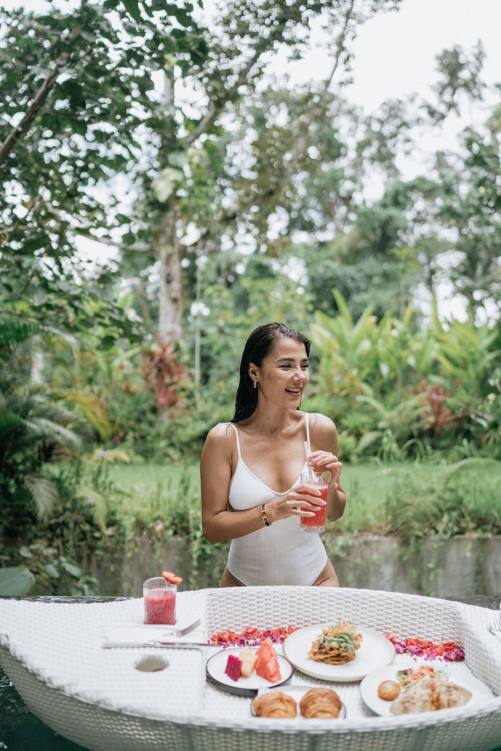 Poolside breakfast spread with tropical fruits and drinks on a floating tray in Bali.