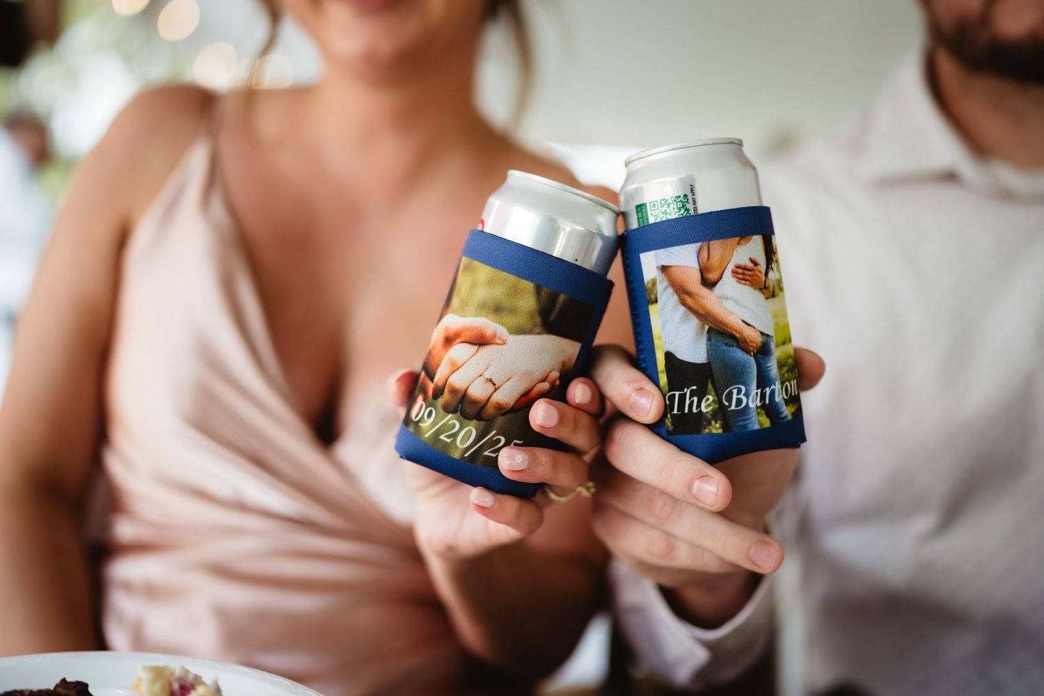 A person holds two Ben and Jerry's ice cream pints while lounging on a soft couch at home.