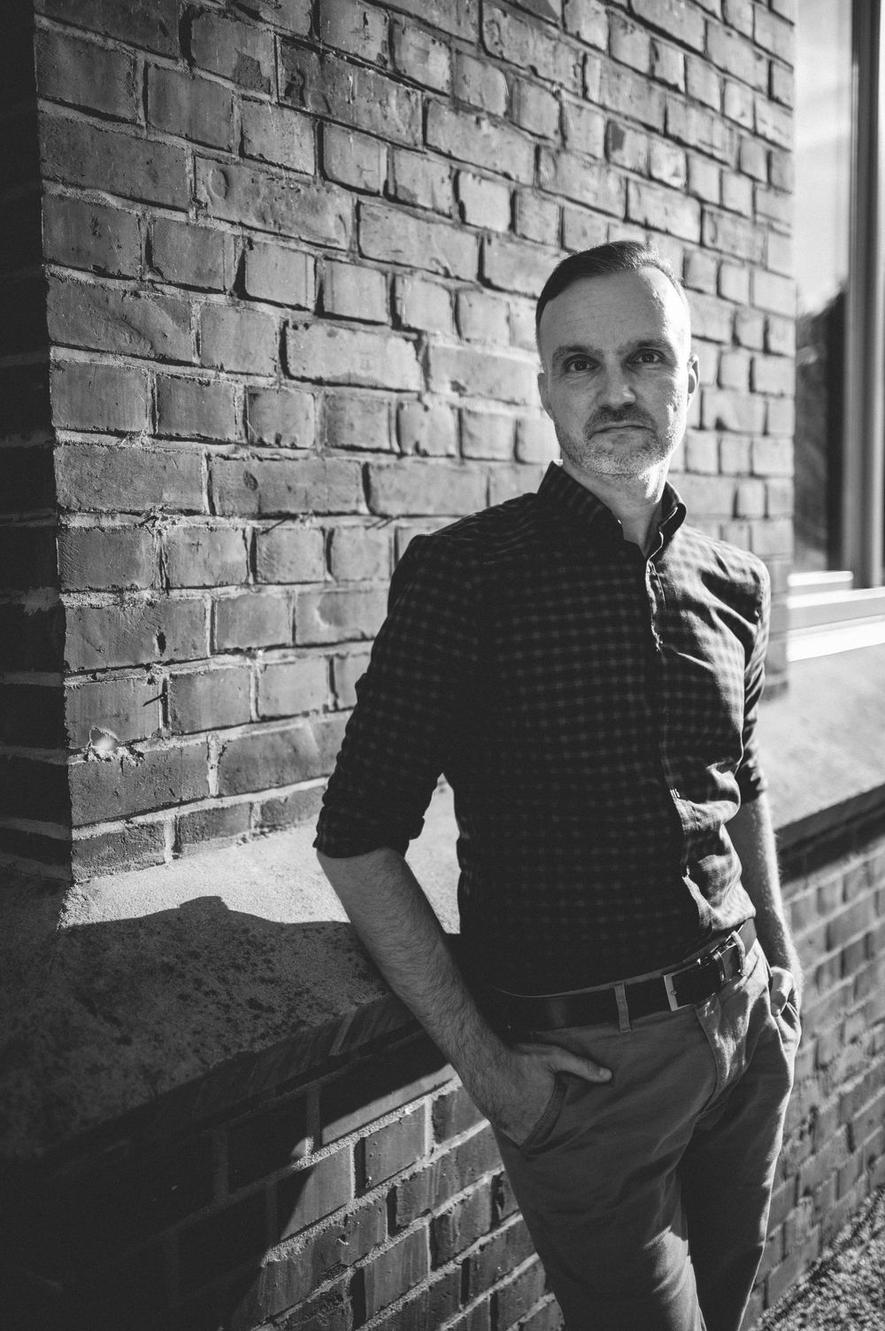 Black and white portrait series showing person leaning against a brick wall in multiple casual poses.