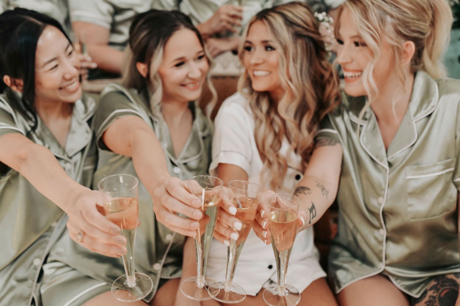 Bride laughing as champagne sprays with her bridesmaids