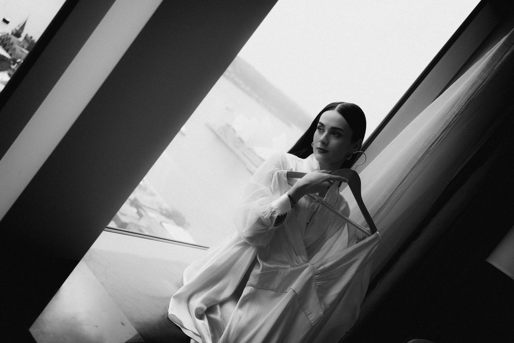 A sequence of dramatic black and white wedding photographs showing preparation moments by a window.