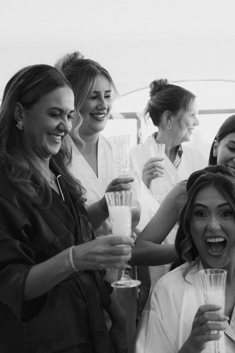 A series of black and white candid shots show a group celebrating with drinks and laughter in a bright setting.