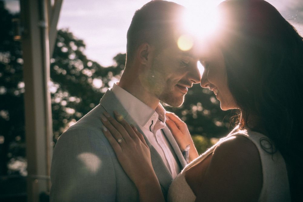 Romantic silhouettes of a couple embracing against bright sunlight during an intimate outdoor moment.