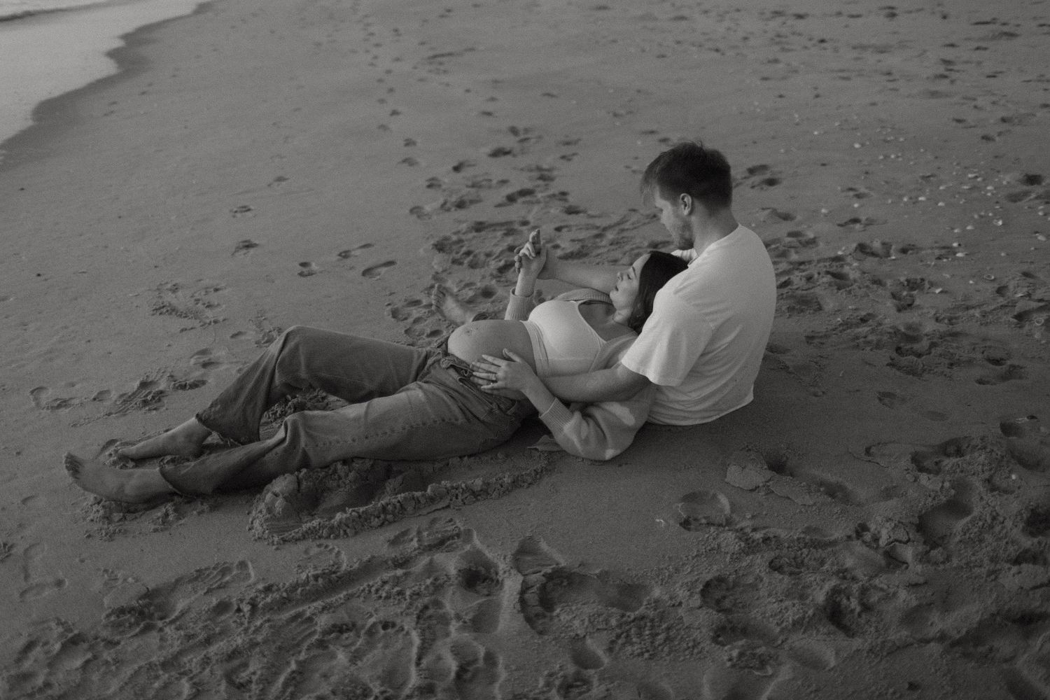 Black and white series of intimate moments captured on beach sand. Sunrise maternity session in Indialantic, Florida.