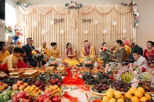A long banquet table decorated with colorful fruits, flowers and platters of food at an elegant event venue.