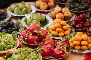 Fresh colorful fruits including grapes, oranges, apples and berries arranged on decorative plates at a market display.
