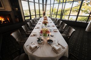 A long banquet table set with white linens and floral centerpieces in an elegant restaurant dining room.