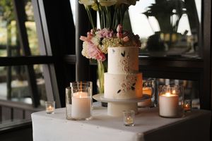 Elegant wedding reception table settings with white candles, floral centerpieces, and soft ambient lighting in a restaurant.