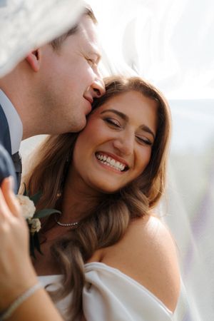 A tender romantic moment captured between a couple on their wedding day showing genuine joy and affection.
