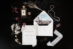 Wedding invitations and envelopes arranged artistically on dark background with dried floral elements.
