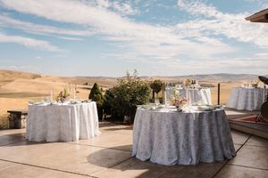 Elegant outdoor wedding reception tables with white linens set against a desert landscape and blue sky backdrop.