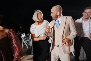 Wedding guests dancing and celebrating together on a dimly lit dance floor during a reception party.