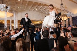 Wedding guests dancing and celebrating together on a lively dance floor under decorative lighting.