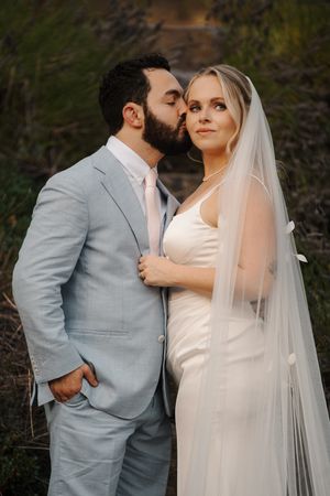 A romantic wedding photo series showing a couple in a grey suit and white dress sharing intimate moments outdoors.
