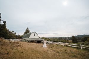 A rustic barn wedding venue with white fencing and rolling hills creates a picturesque countryside setting.
