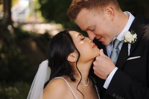 Intimate wedding moment captured between newlyweds sharing a tender kiss outdoors in natural lighting.